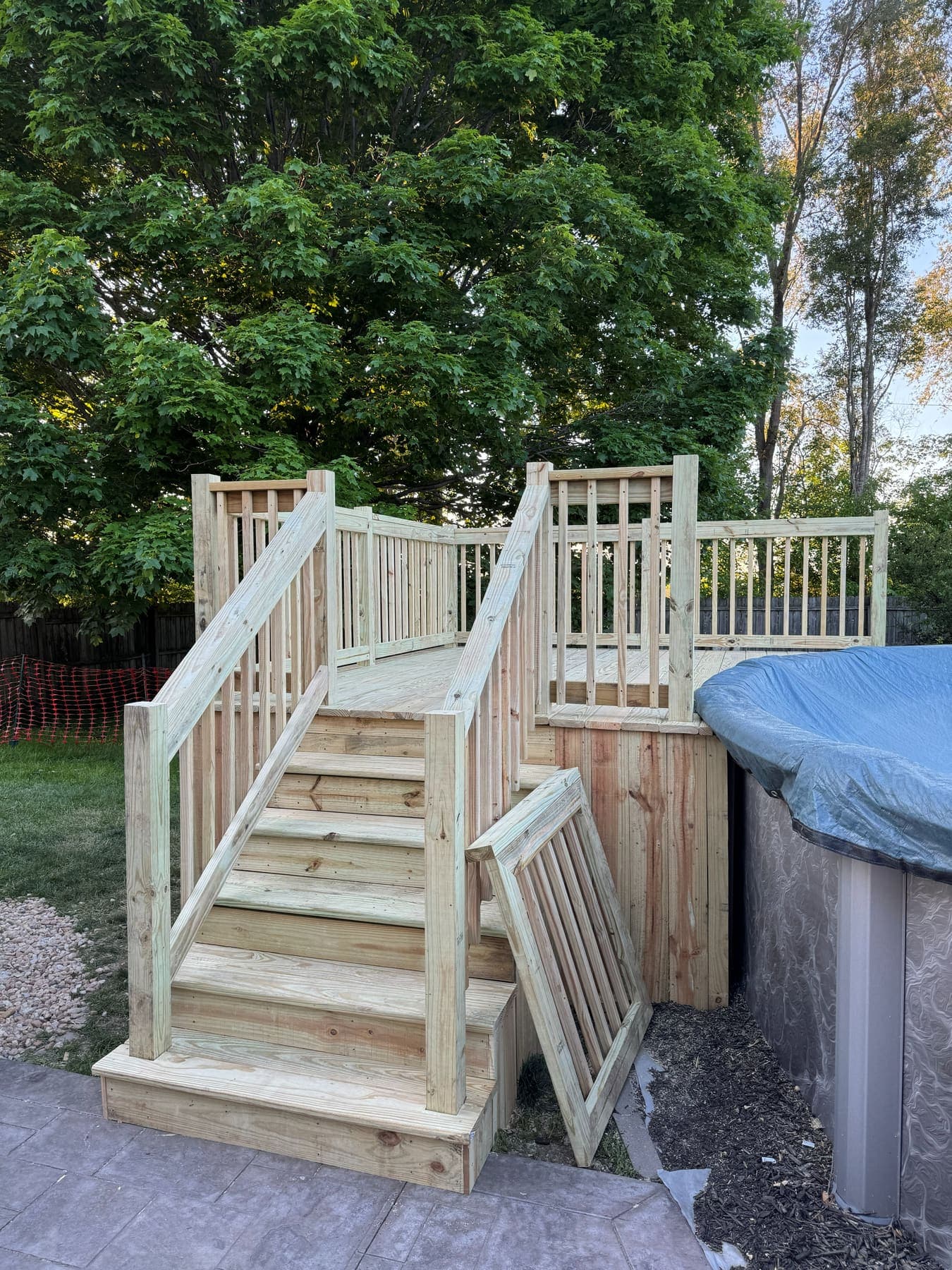 Treated wood pool deck with a framed stair run, handrails both sides and a hinged access panel