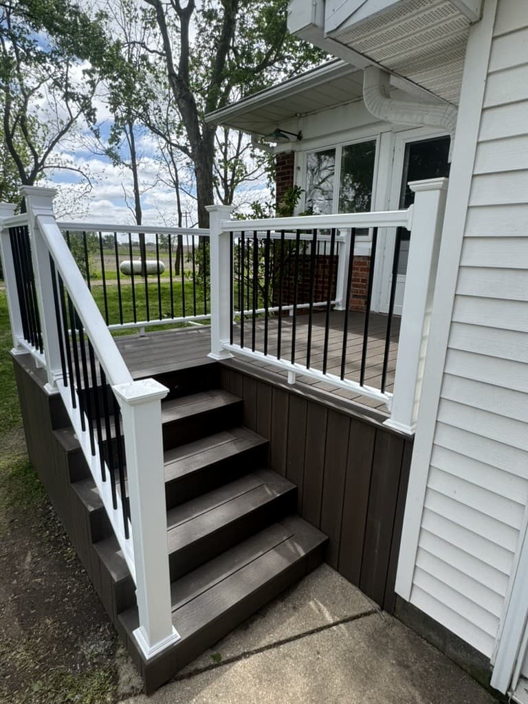 Composite deck stairs against white siding with white rail