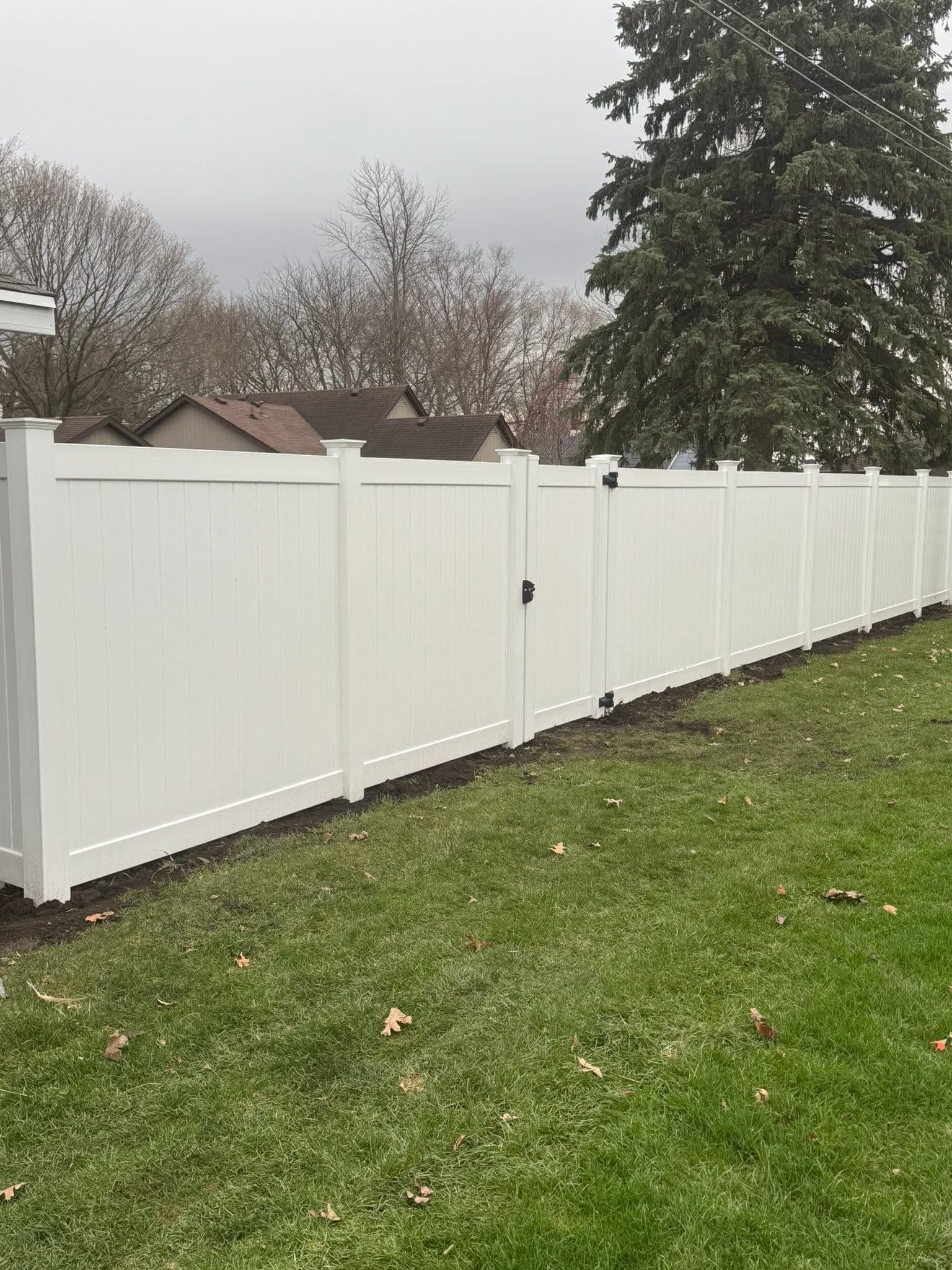 White vinyl privacy fence with a walk gate and black hardware