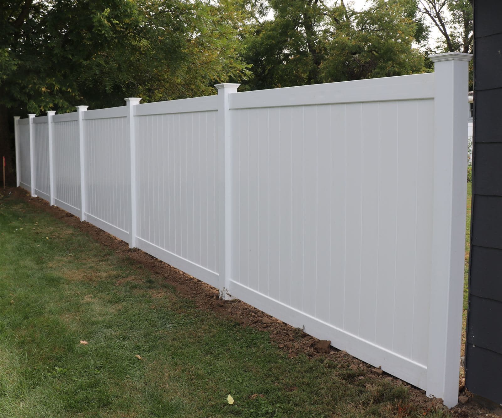 Long run of white vinyl privacy fence wrapping a backyard corner