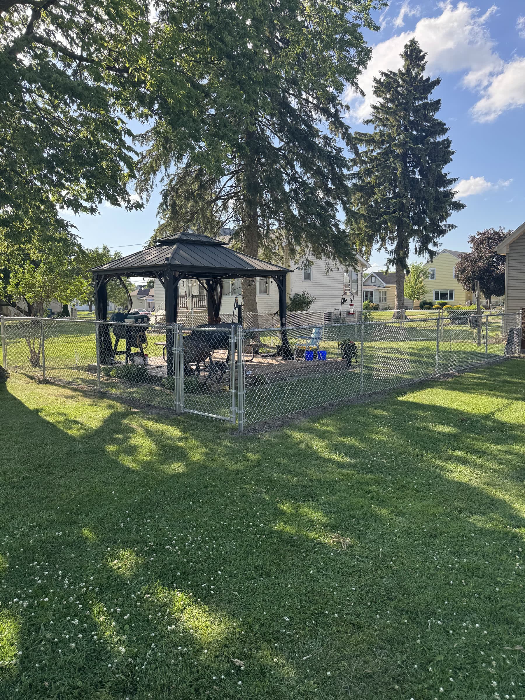 Galvanized chain-link fence enclosing a back yard with a gazebo, installed by Xcel Outdoor Living
