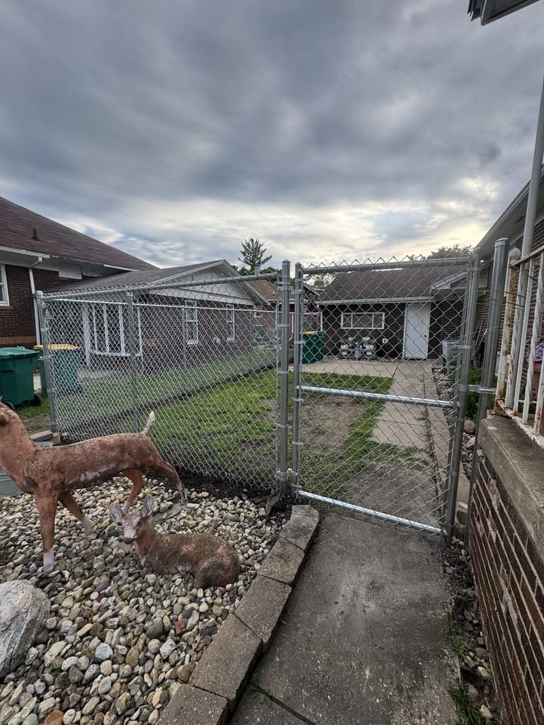 Galvanized chain-link run with a walk gate enclosing a back yard, installed by Xcel Outdoor Living