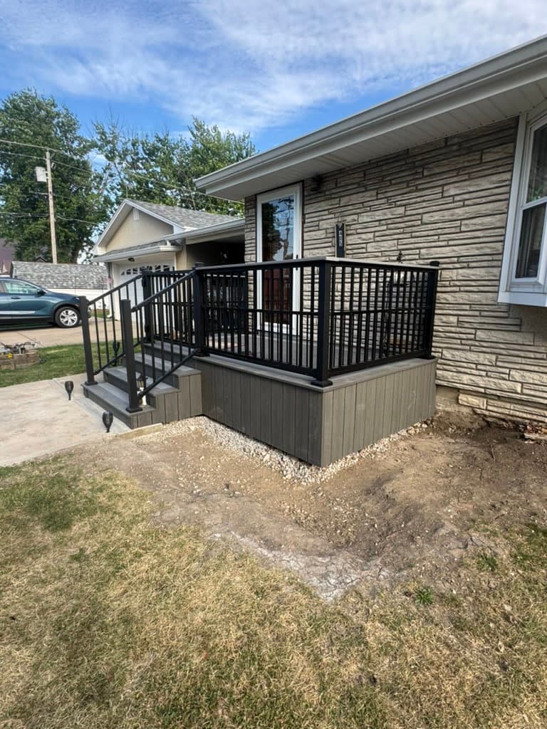 Black aluminum railing with square balusters around a composite front deck built by Xcel Outdoor Living