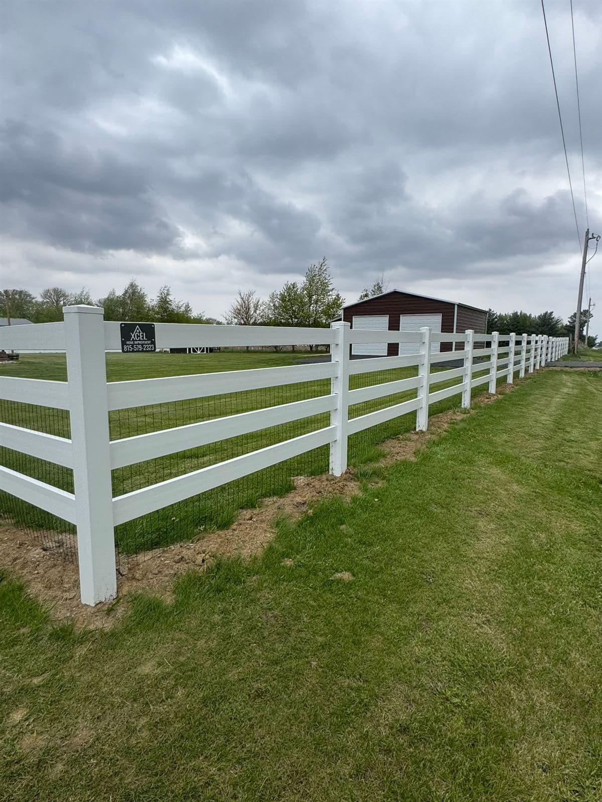 Four rail white vinyl ranch fence running across a large lawn