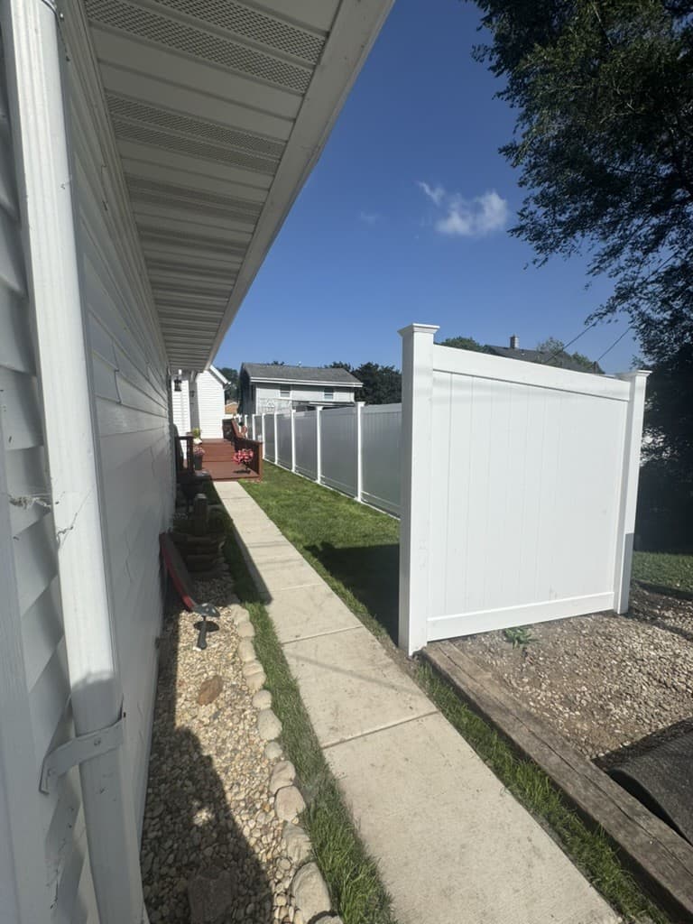 White vinyl privacy fence along a side yard, built by Xcel Outdoor Living in LaSalle County, Illinois