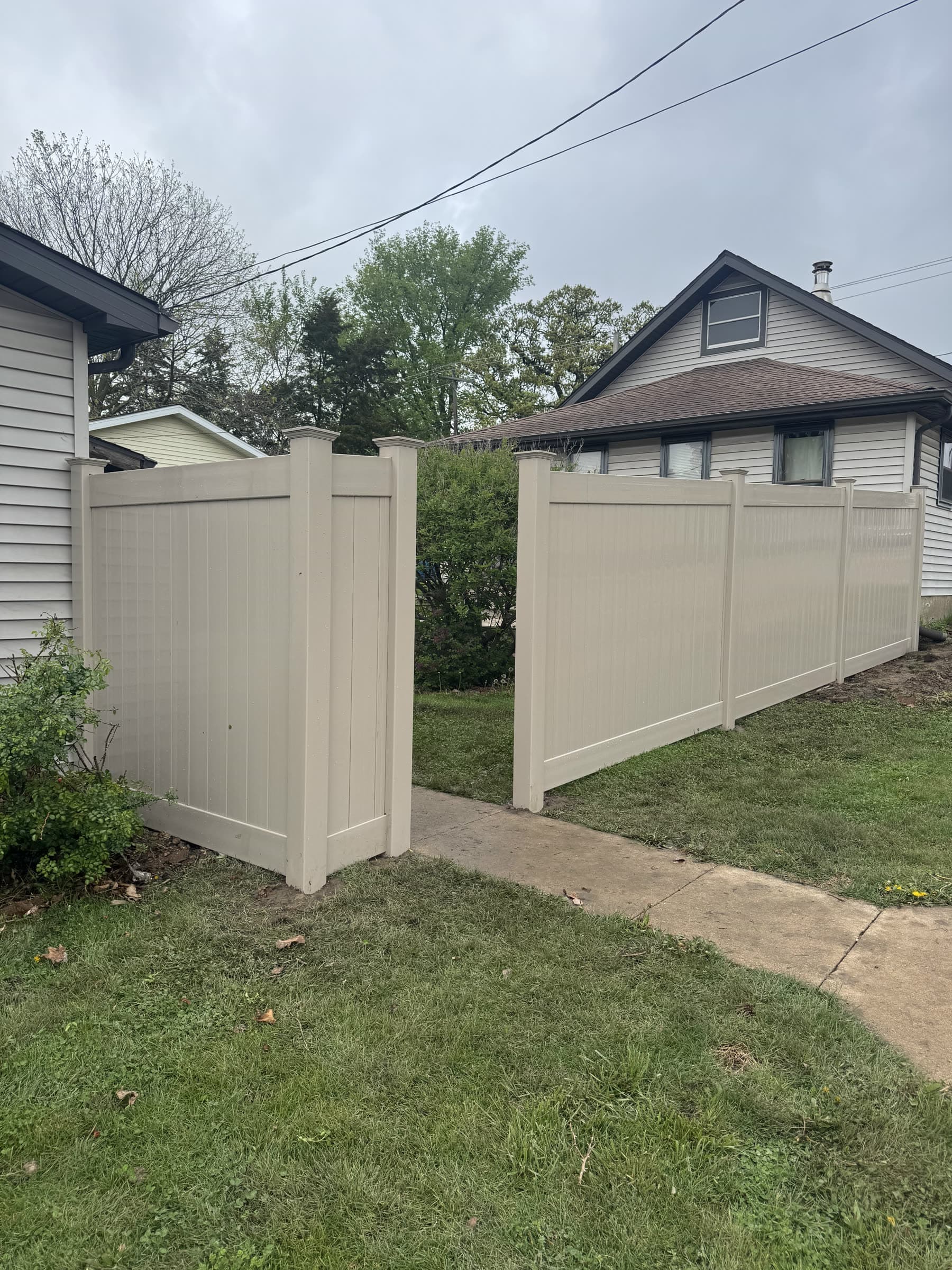 Tan vinyl privacy fence installed by Xcel Outdoor Living, showing vinyl in a color other than white