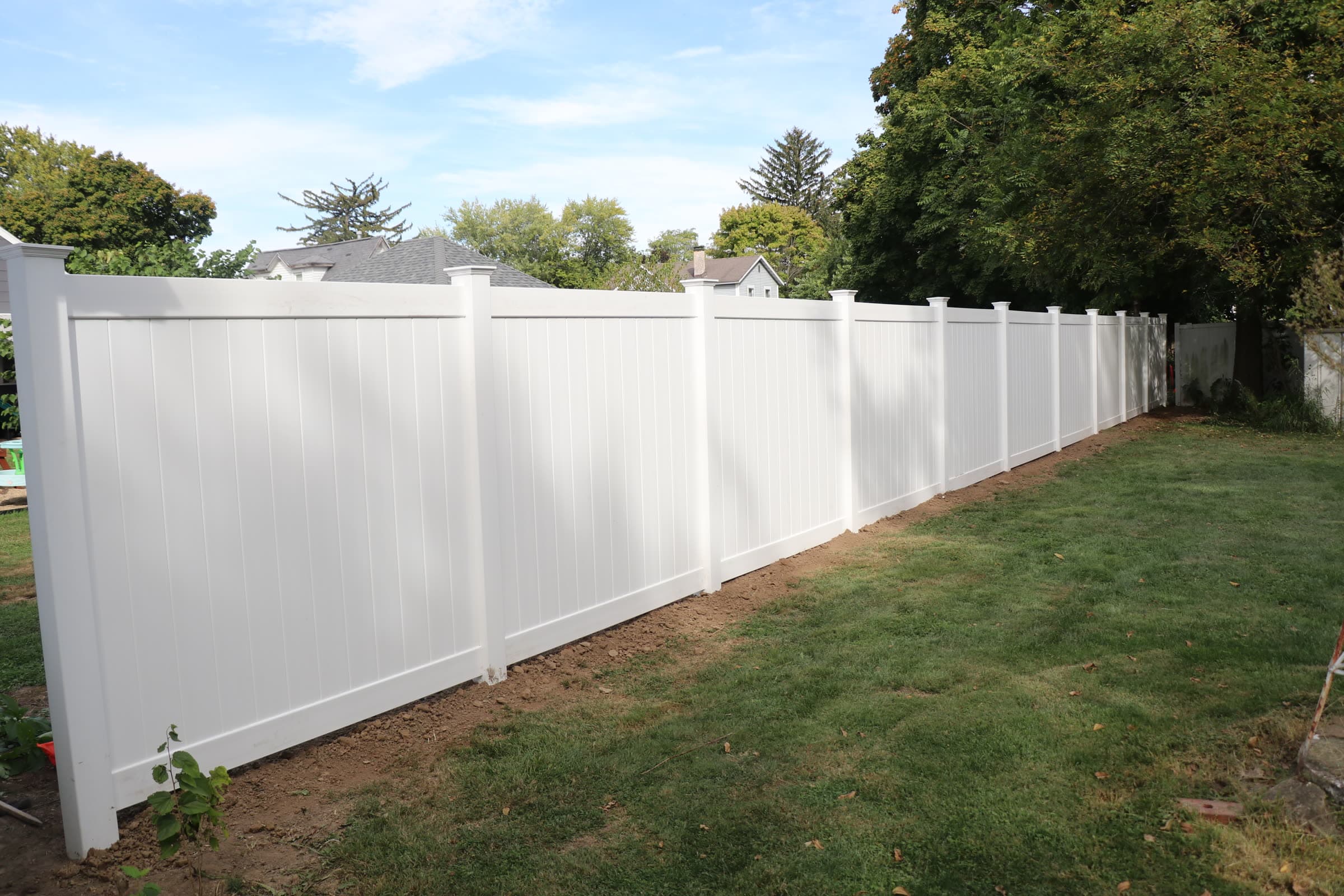 White vinyl privacy fence running the length of a back yard, installed by Xcel Outdoor Living in the Illinois Valley
