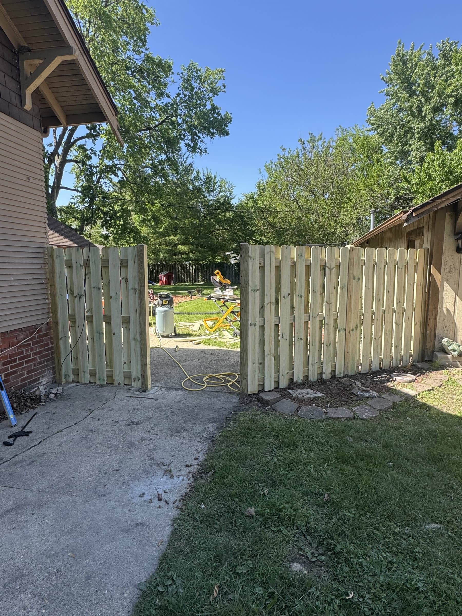 Shadowbox wood privacy fence and matching gate installed by Xcel Outdoor Living, boards alternating on either side of the rail